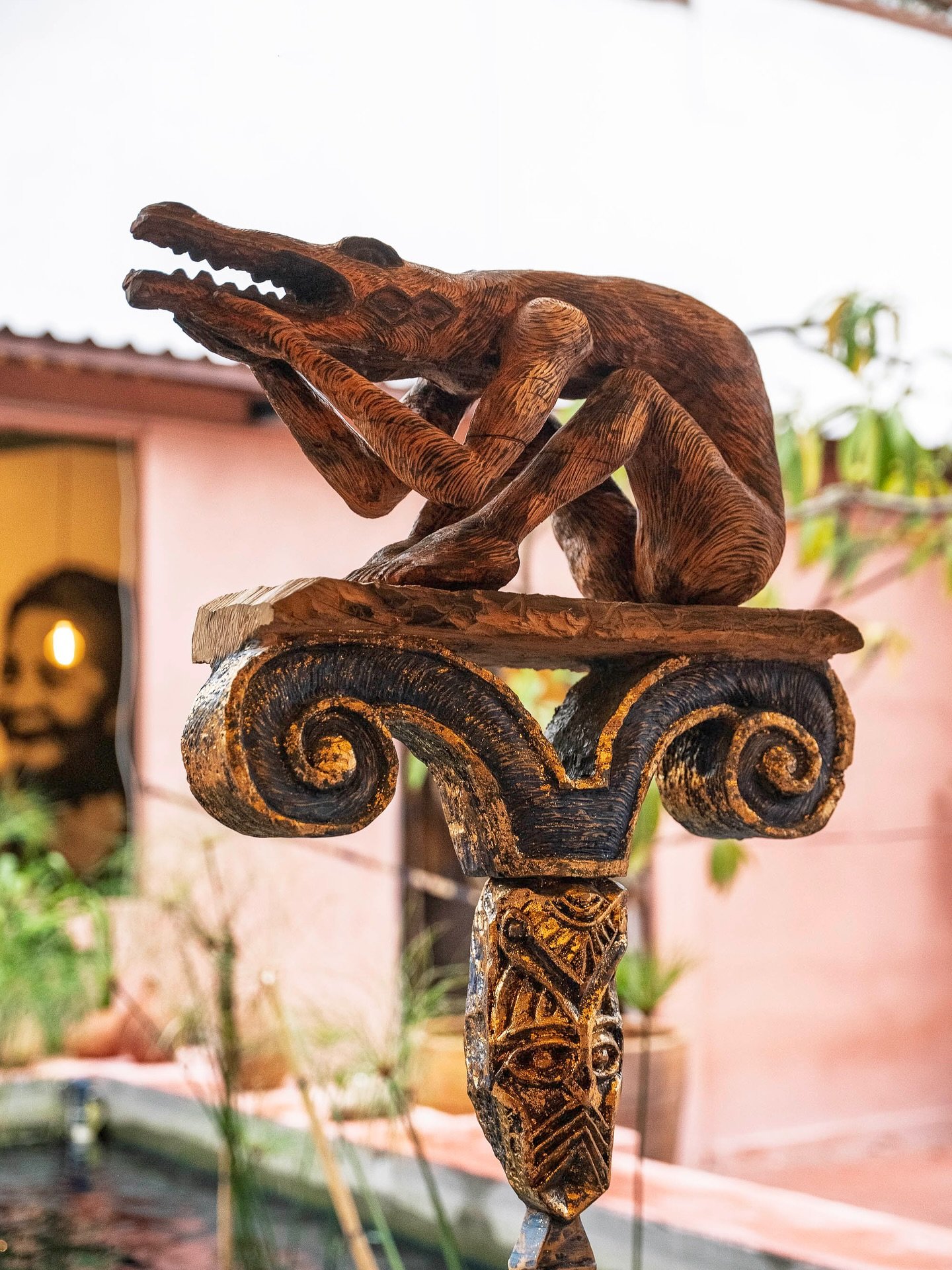 Escultura de madera tallada de una figura animal con una flauta, en el patio del restaurante.
