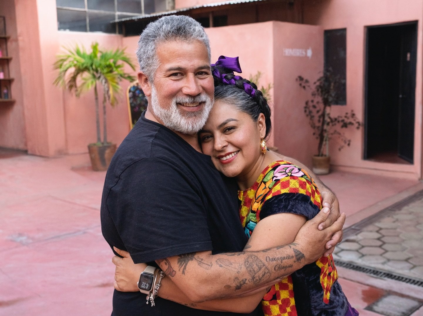 Dos personas se abrazan y sonríen en el patio de Zapoteca.